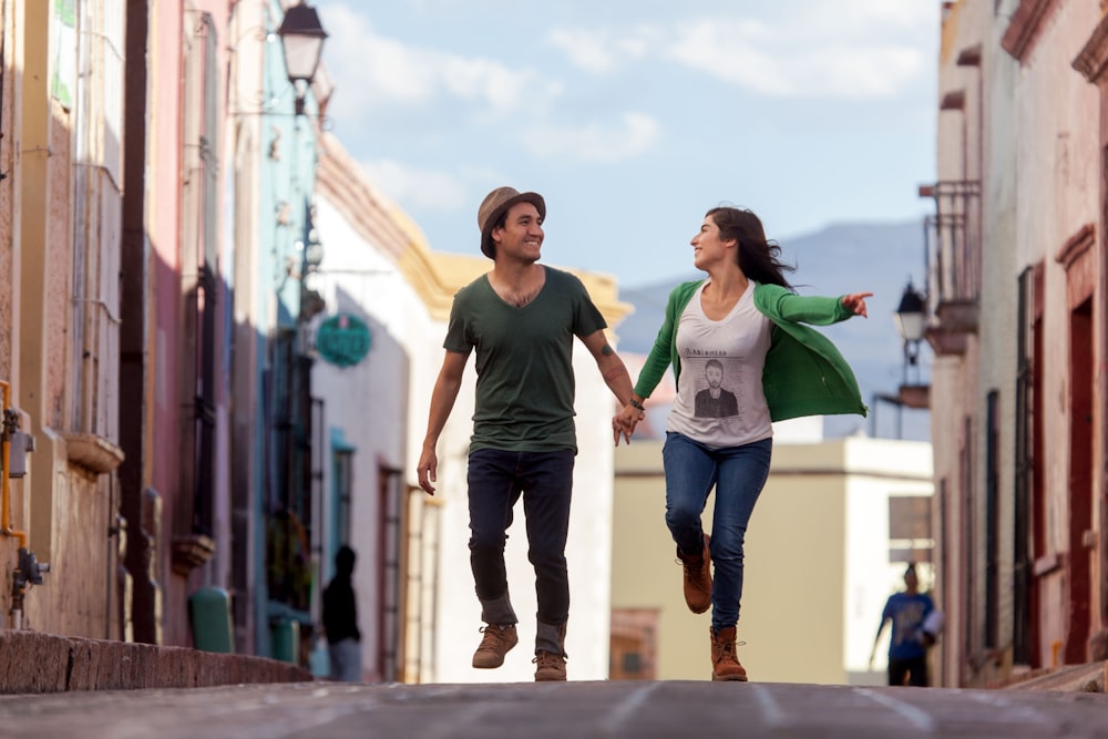 녹색 티셔츠를 입은 남자와 흰색 티셔츠를 입은 여자가 낮에 거리를 걷고 있다