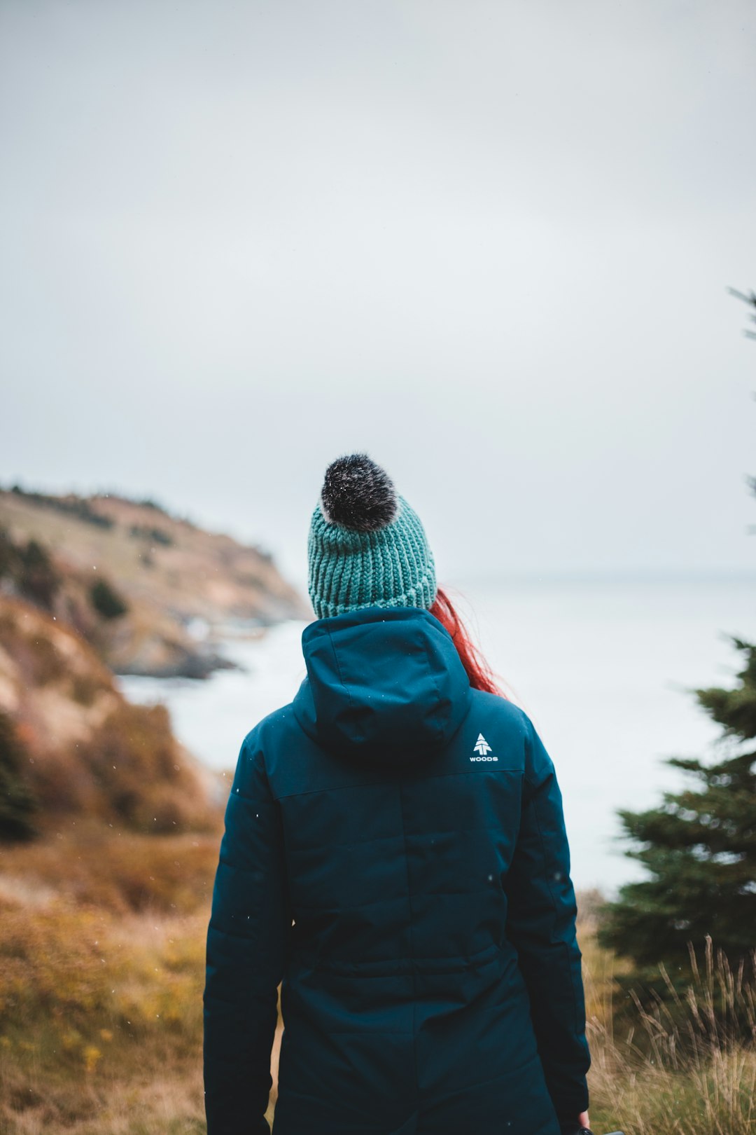 person in black and red hoodie standing near green trees during daytime