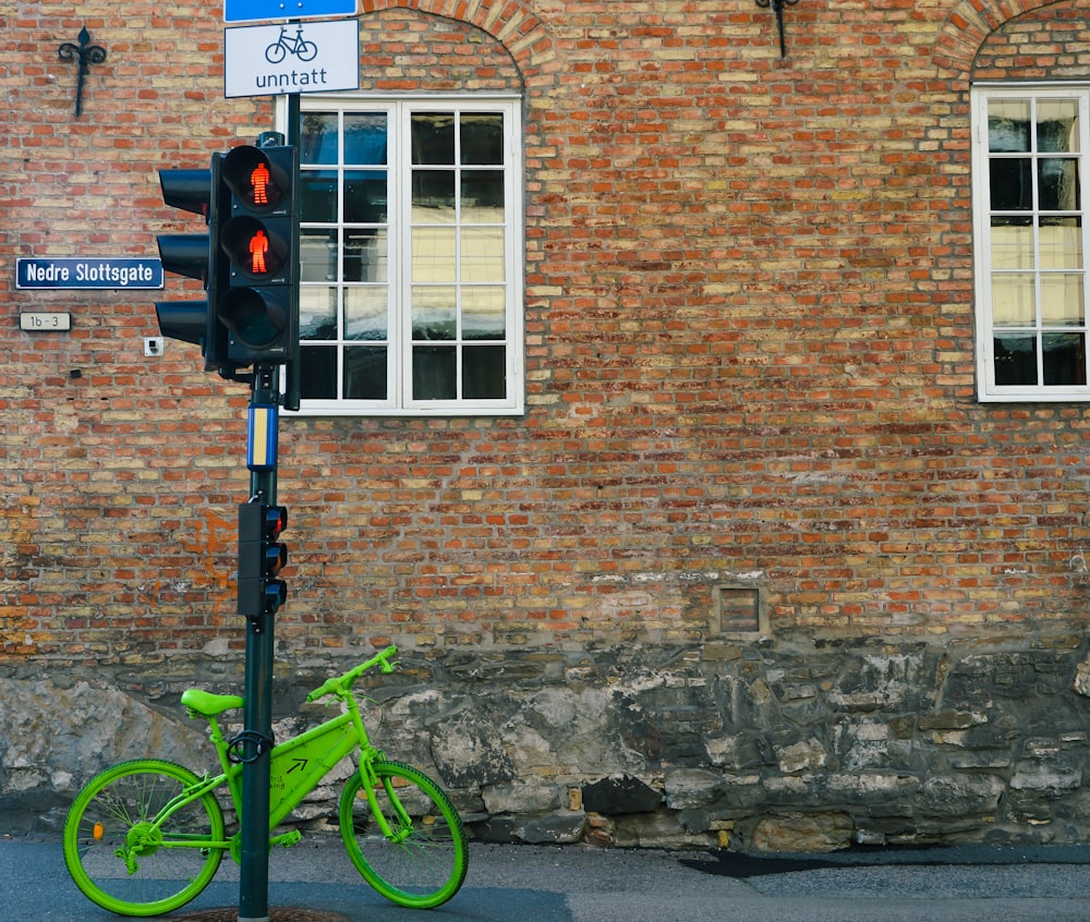 green and black road bike beside brown brick wall