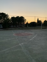 Evening view of a basketball court with high-quality safety nets glowing under floodlights.