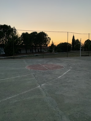 Evening view of a basketball court with high-quality safety nets glowing under floodlights.