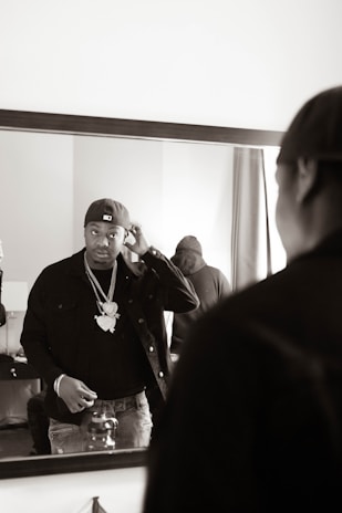 A stylish influencer adjusting his tailored jacket in front of a mirror, blending fashion with a subtle fragrance mist.