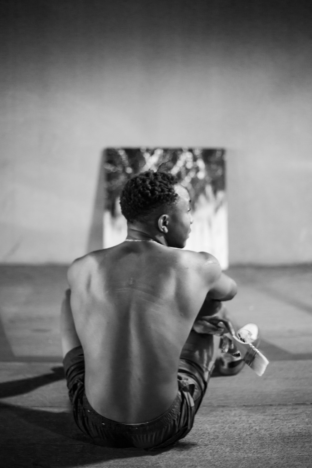 topless man in shorts sitting on floor