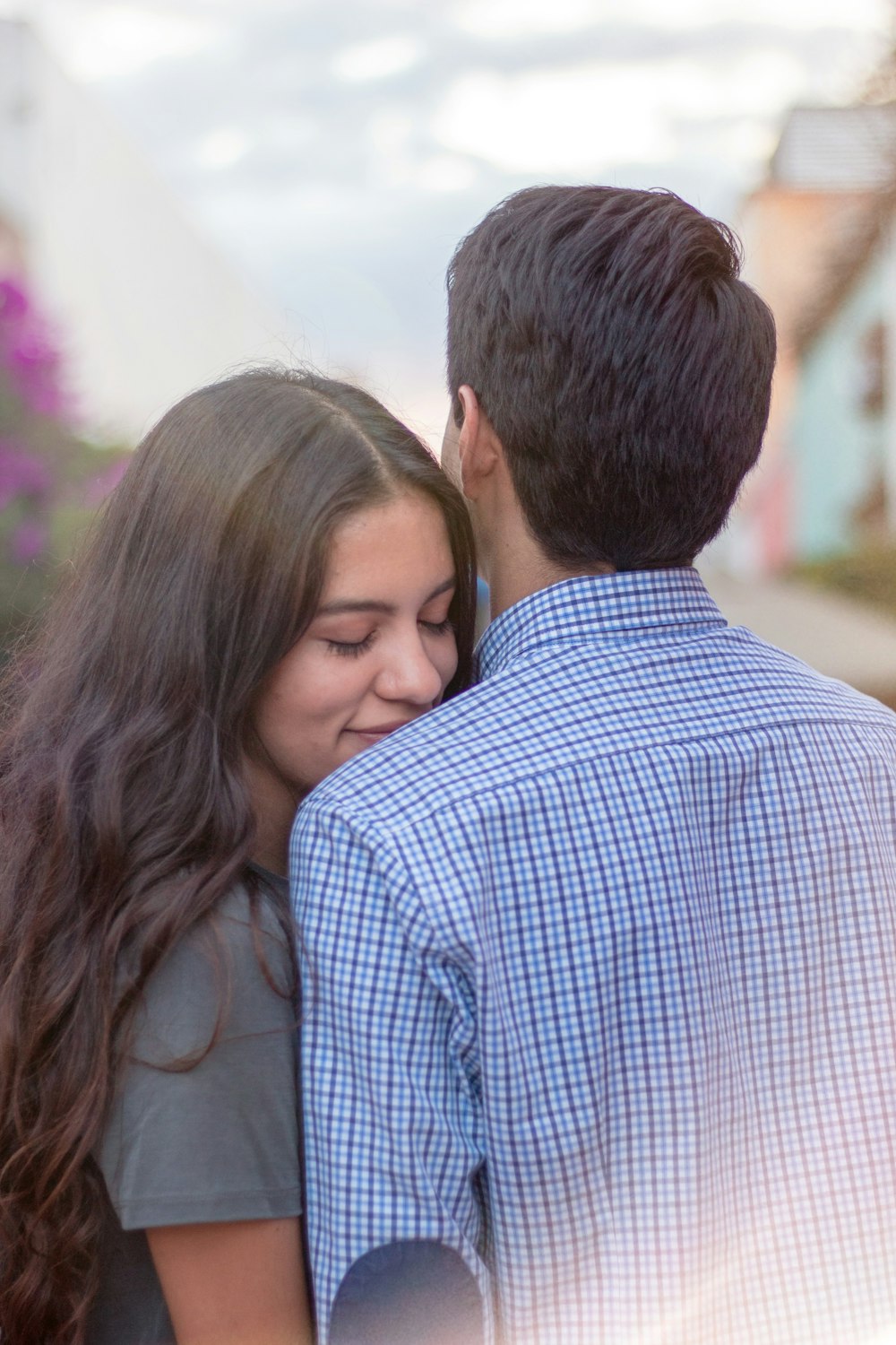 man in blue and white checkered dress shirt kissing woman in gray shirt