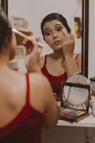 A model applying makeup in front of a mirror.