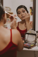 A close-up of a person applying colorful eyeshadow while looking into a handheld mirror.