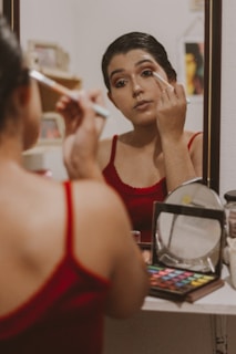 A model applying makeup in front of a mirror.