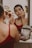 A woman applying makeup in front of a mirror, looking confident.