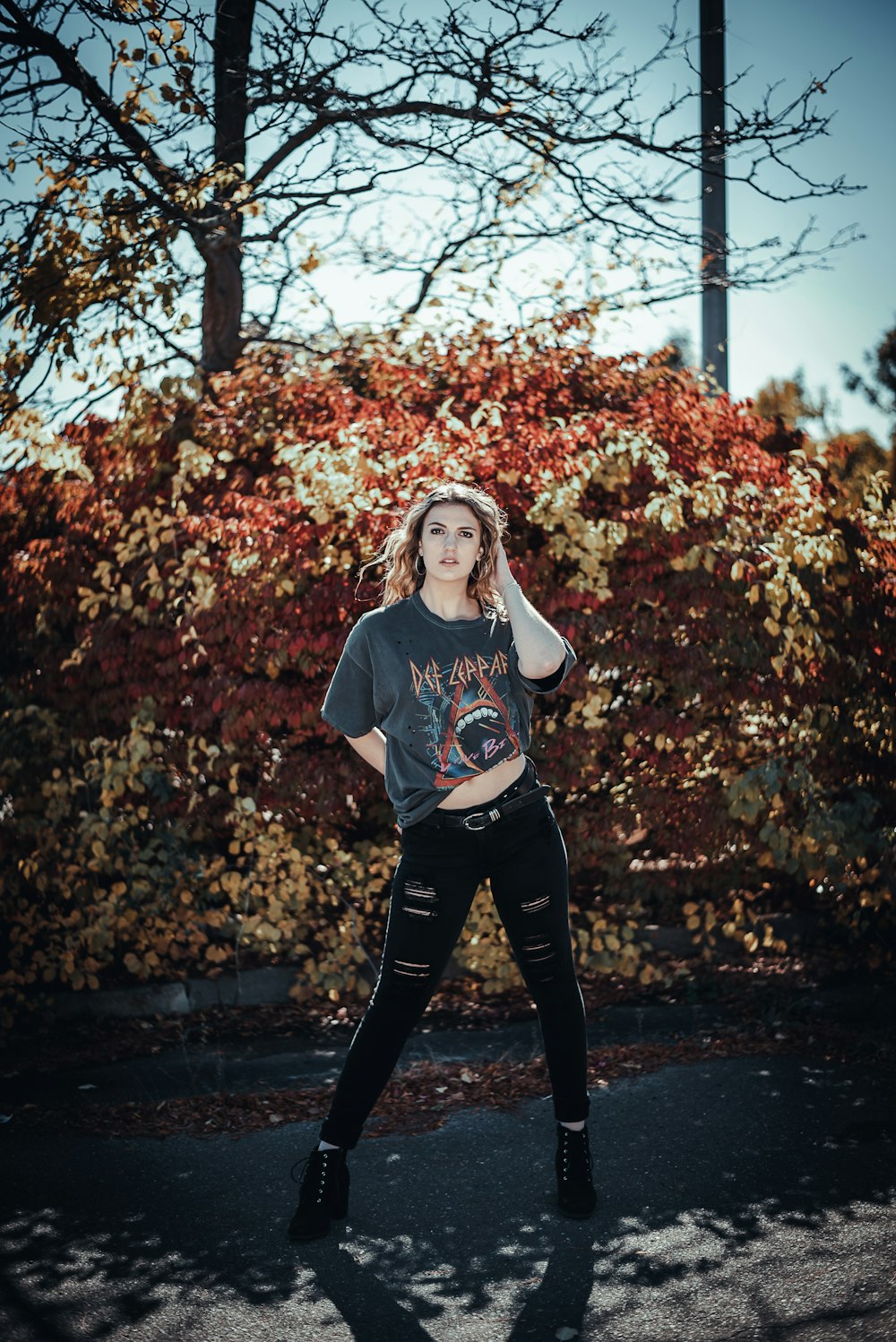 woman in black crew neck t-shirt and black pants standing on black asphalt road during