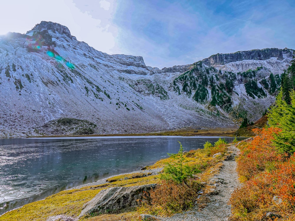 green and gray mountain beside lake under blue sky during daytime