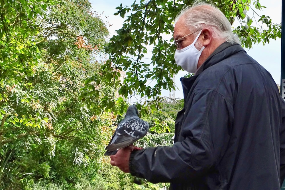 man in black jacket holding gray bird