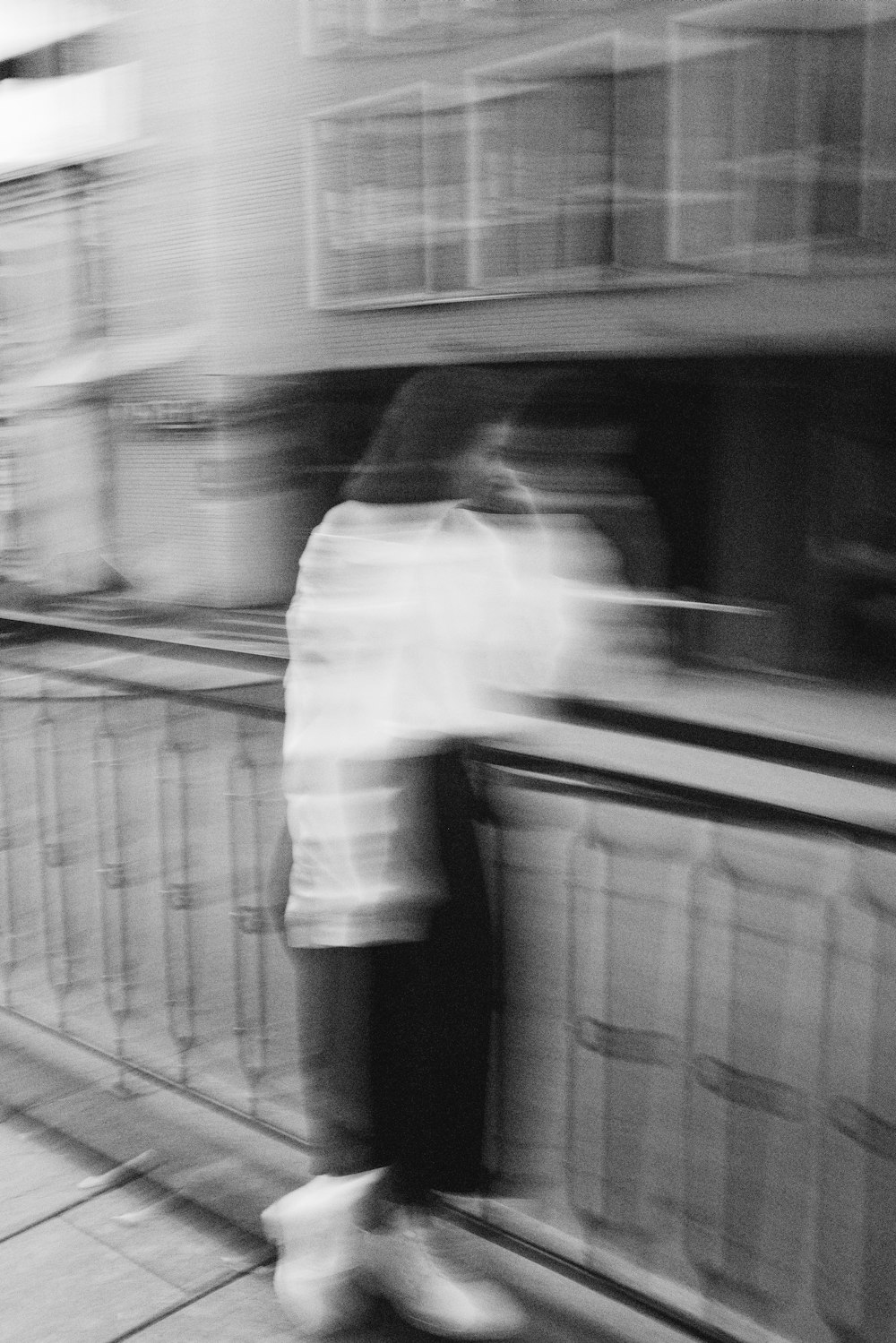 grayscale photo of man in white dress shirt and black pants standing on train station