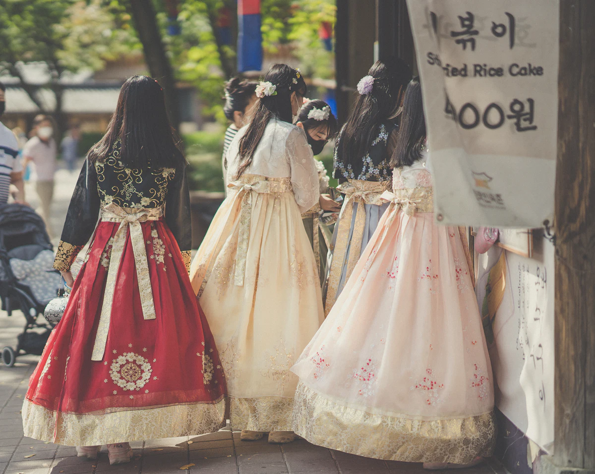 Women in colourful hanbok walking through a Korean street market
