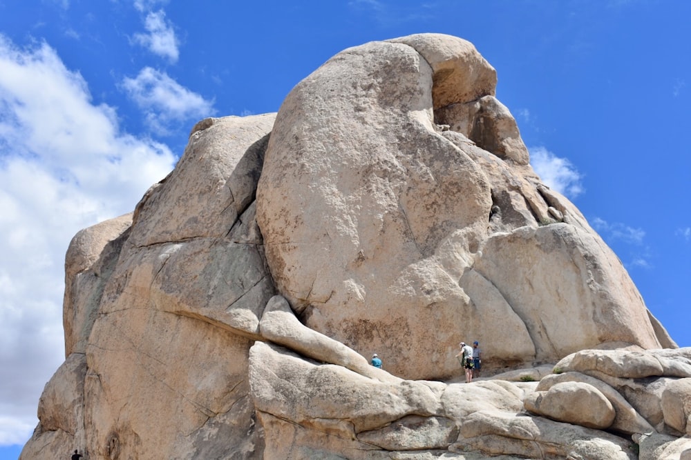 people climbing rock formation under blue sky during daytime