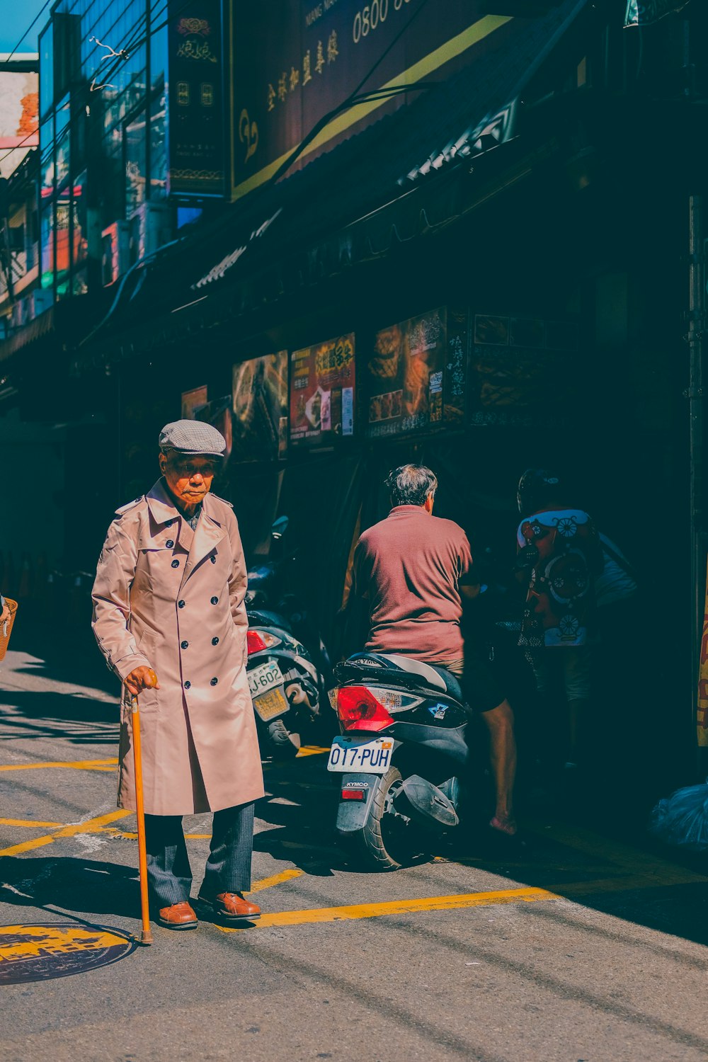 man in brown coat standing near black and red motorcycle during daytime