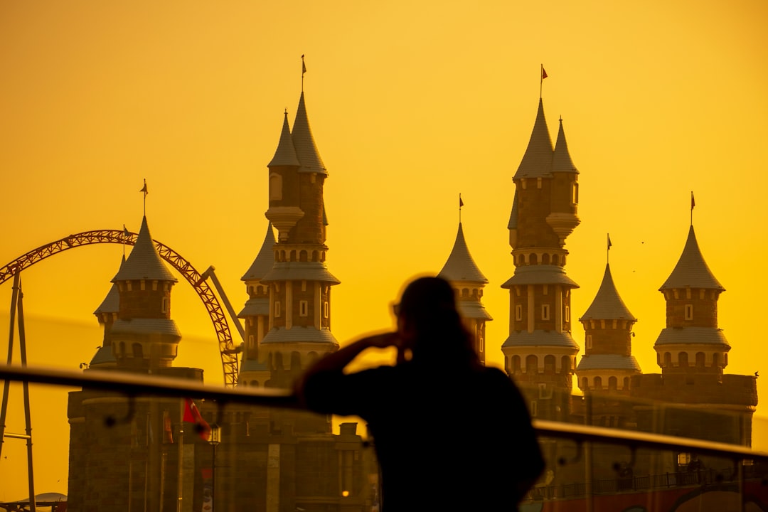 silhouette of woman standing near white concrete building during sunset