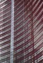Steel and glass building facade with red horizontal slats creating a dynamic, modern architectural design.