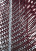 Steel and glass building facade with red horizontal slats creating a dynamic, modern architectural design.