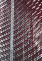 Steel and glass building facade with red horizontal slats creating a dynamic, modern architectural design.