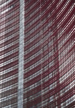 Steel and glass building facade with red horizontal slats creating a dynamic, modern architectural design.
