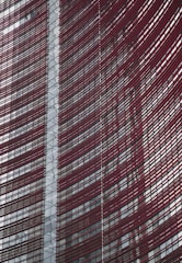 Steel and glass building facade with red horizontal slats creating a dynamic, modern architectural design.