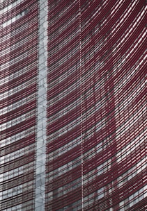 Steel and glass building facade with red horizontal slats creating a dynamic, modern architectural design.
