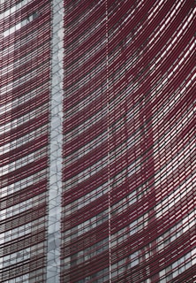 Steel and glass building facade with red horizontal slats creating a dynamic, modern architectural design.
