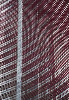 Steel and glass building facade with red horizontal slats creating a dynamic, modern architectural design.