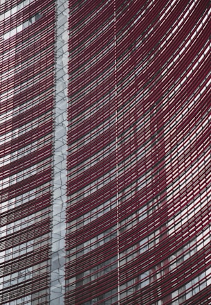 Steel and glass building facade with red horizontal slats creating a dynamic, modern architectural design.