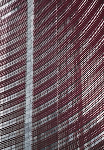Steel and glass building facade with red horizontal slats creating a dynamic, modern architectural design.