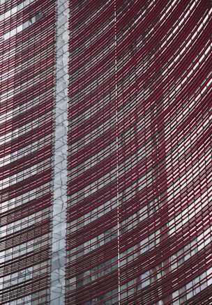 Steel and glass building facade with red horizontal slats creating a dynamic, modern architectural design.