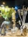 A warmly lit shop window display features a variety of home decor items. On the left, there's an ornate vase with pale yellow flowers. In front are jars and bottles labeled with the brand 'Zielinski & Rozen', a candle on a gold stand, and a horse-head figurine. To the right, a large amber bottle with white reeds sticks is displayed.