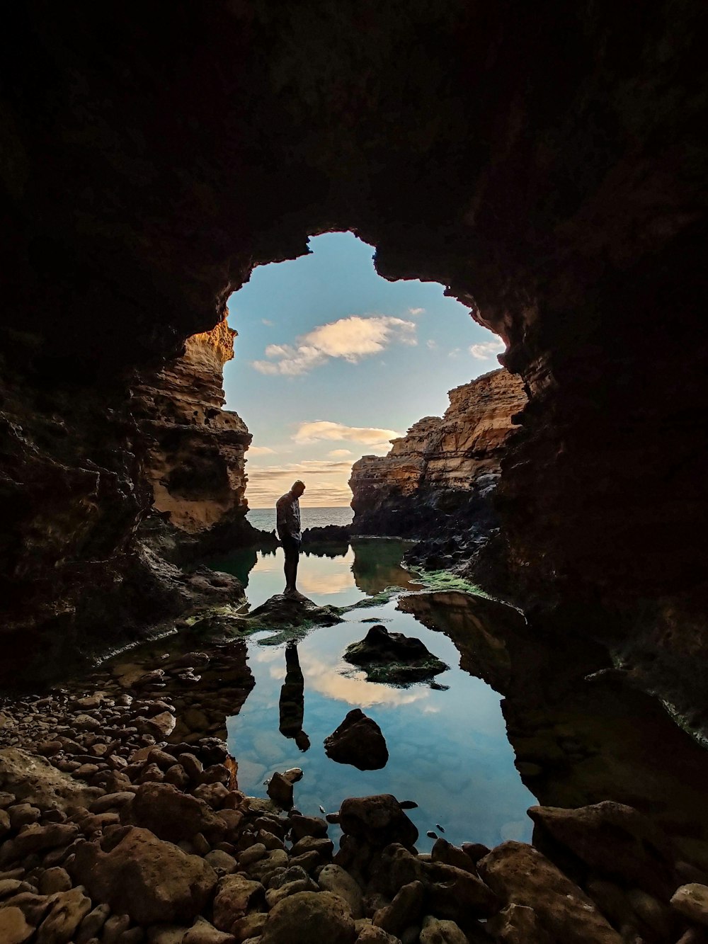 man standing on rock formation near body of water during daytime