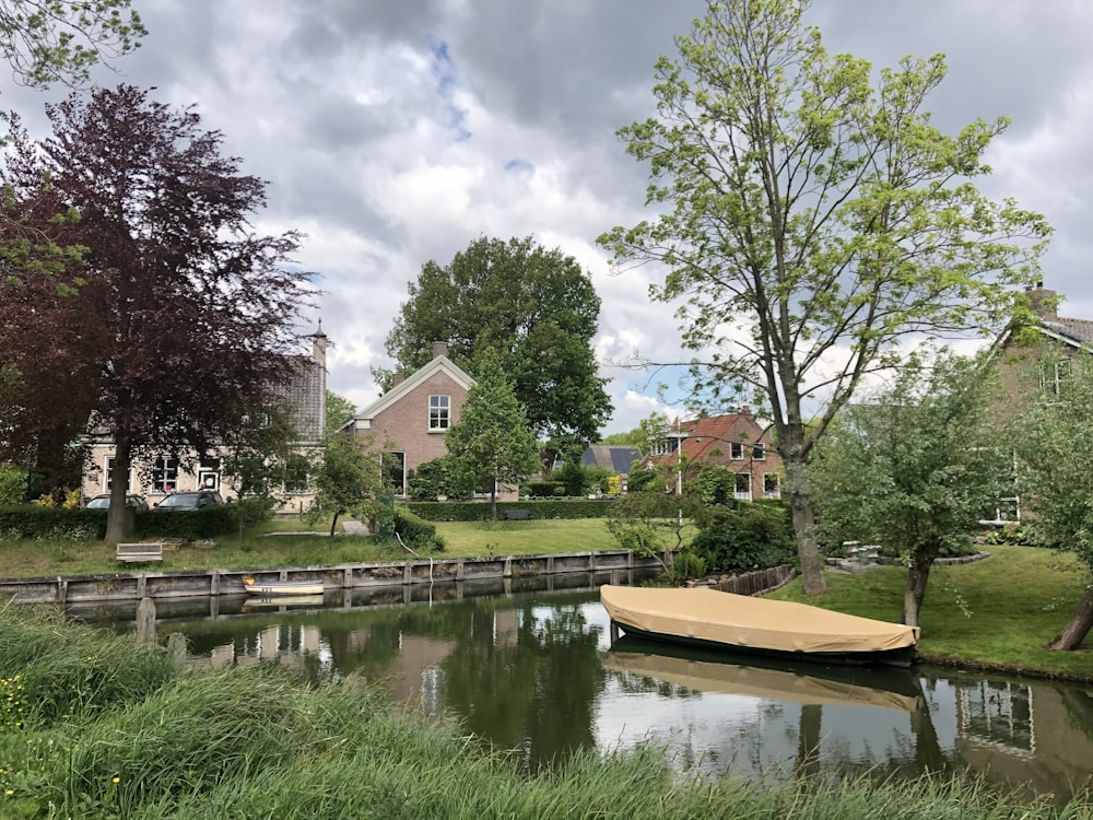 brown boat on river near green trees during daytime