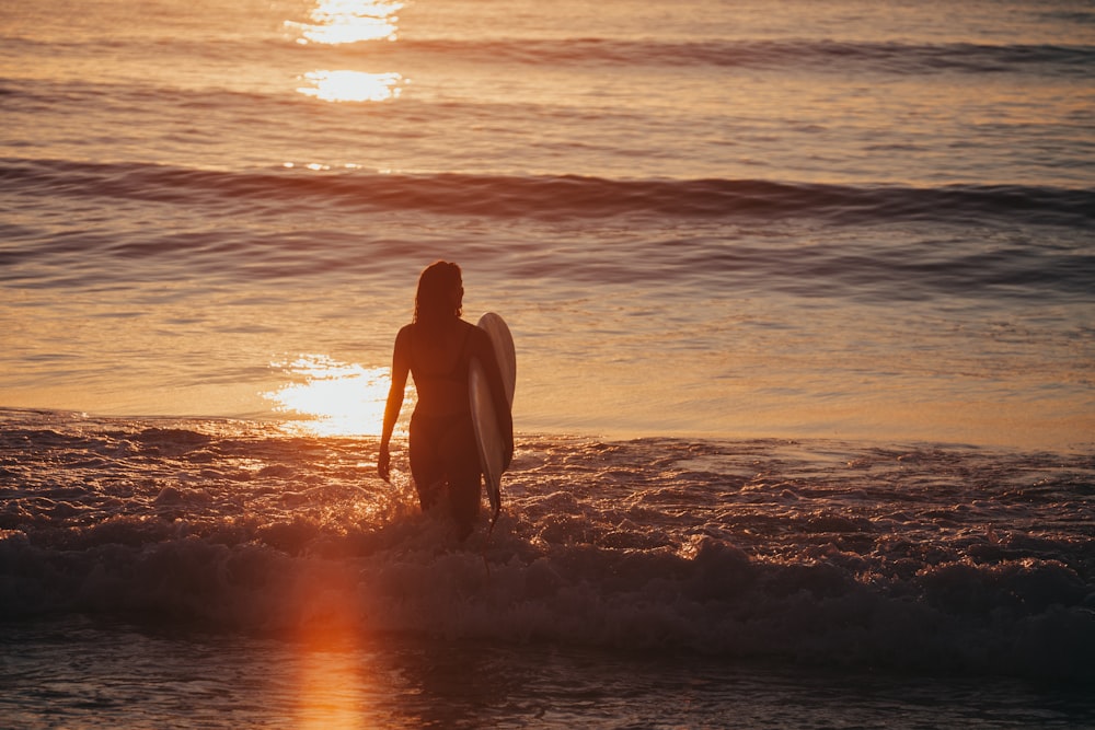 woman in black bikini sitting on beach during sunset