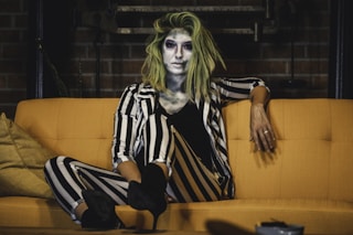 woman in black and white stripe dress sitting on orange sofa