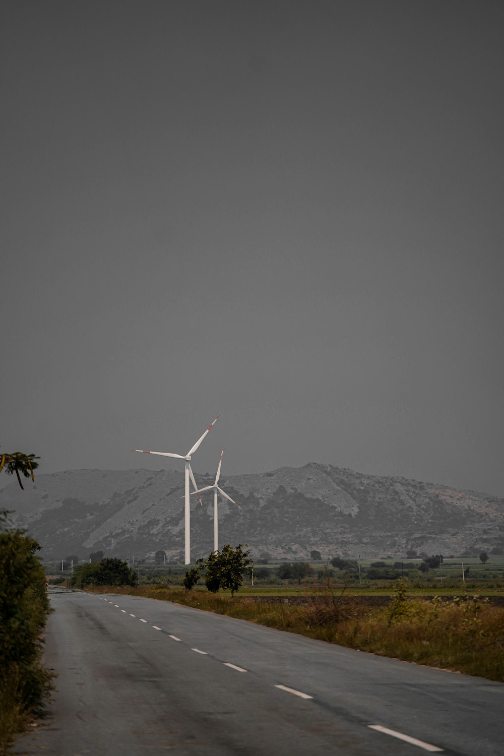 white wind turbines on gray asphalt road during daytime