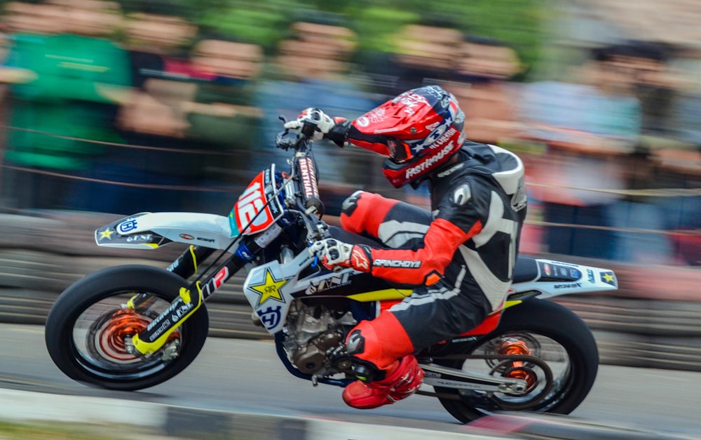 man in red and black motorcycle suit riding on red and black sports bike