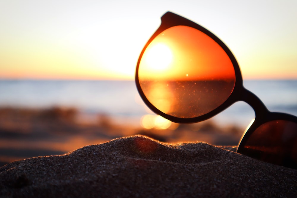 black magnifying glass on brown sand during sunset