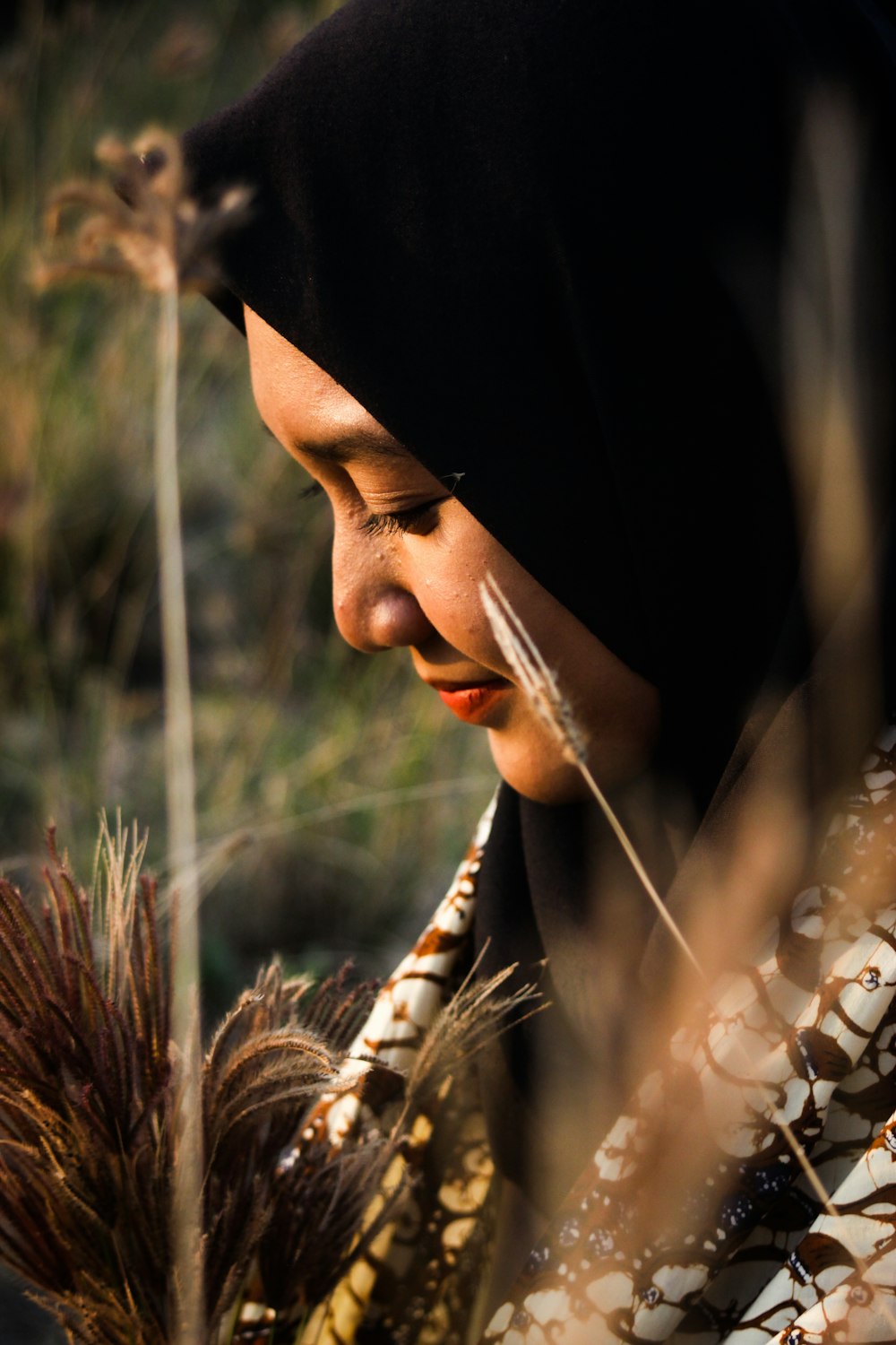 woman in black hijab holding brown wheat