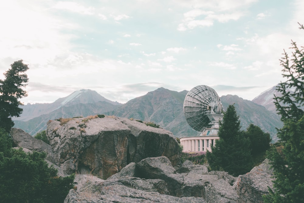 edificio in cemento bianco vicino alla montagna sotto nuvole bianche durante il giorno