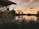 brown wooden house near lake during sunset