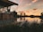 brown wooden house near lake during sunset