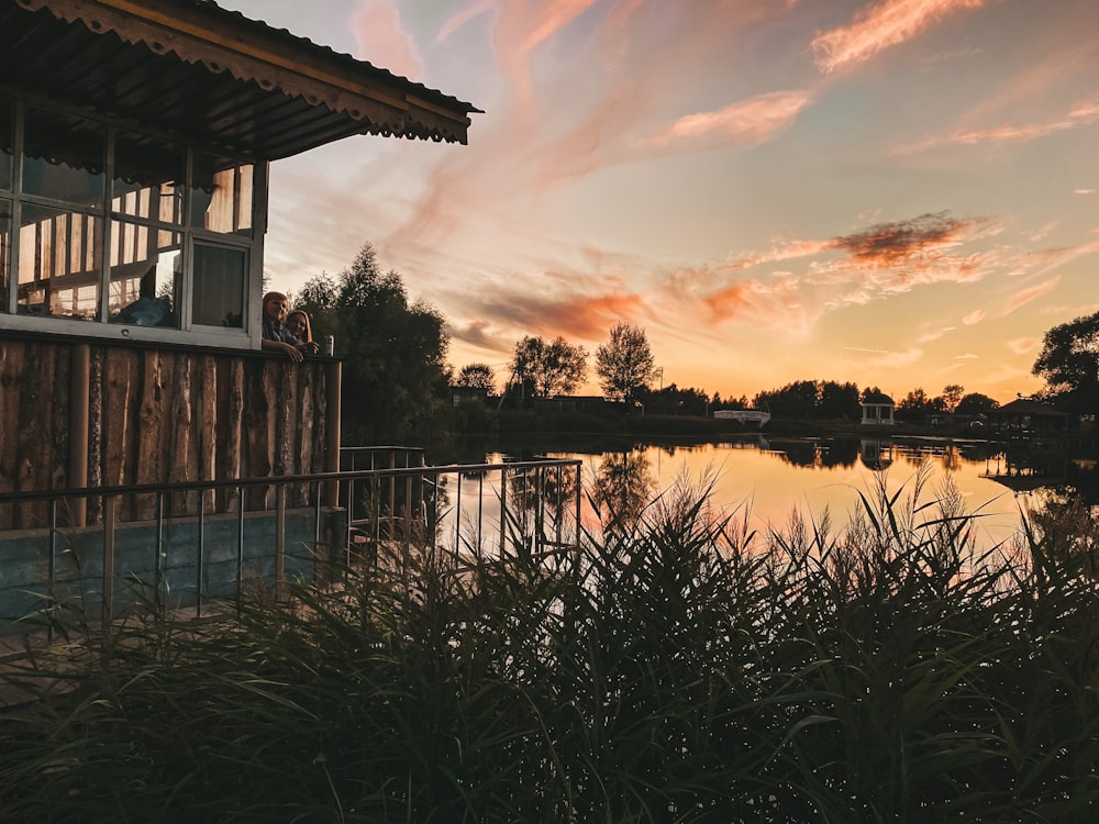 brown wooden house near lake during sunset