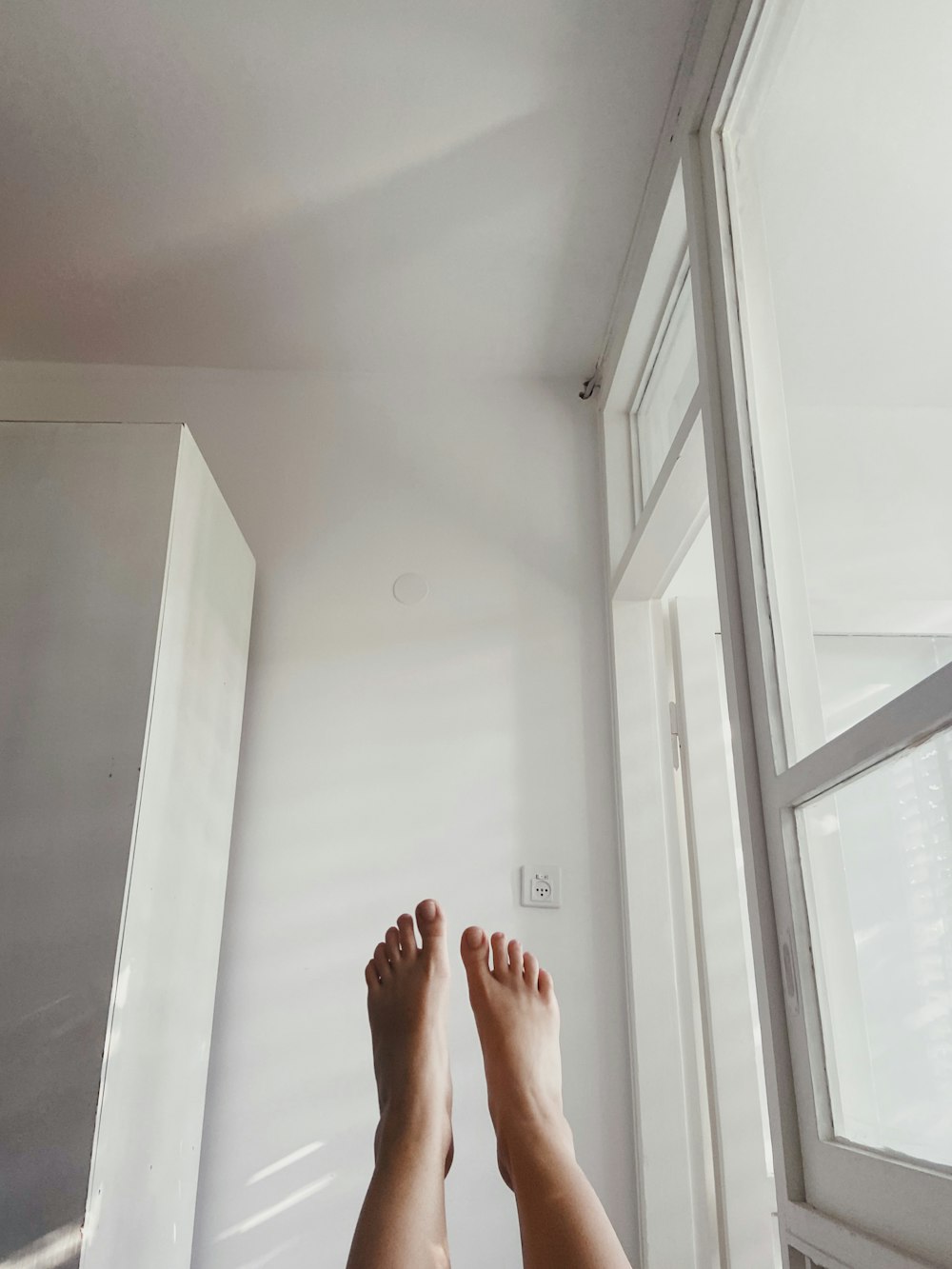 persons feet on white wall