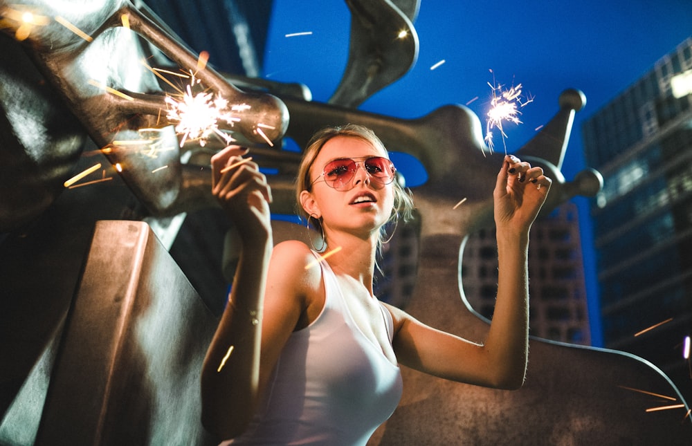 a woman holding a sparkler in front of a statue