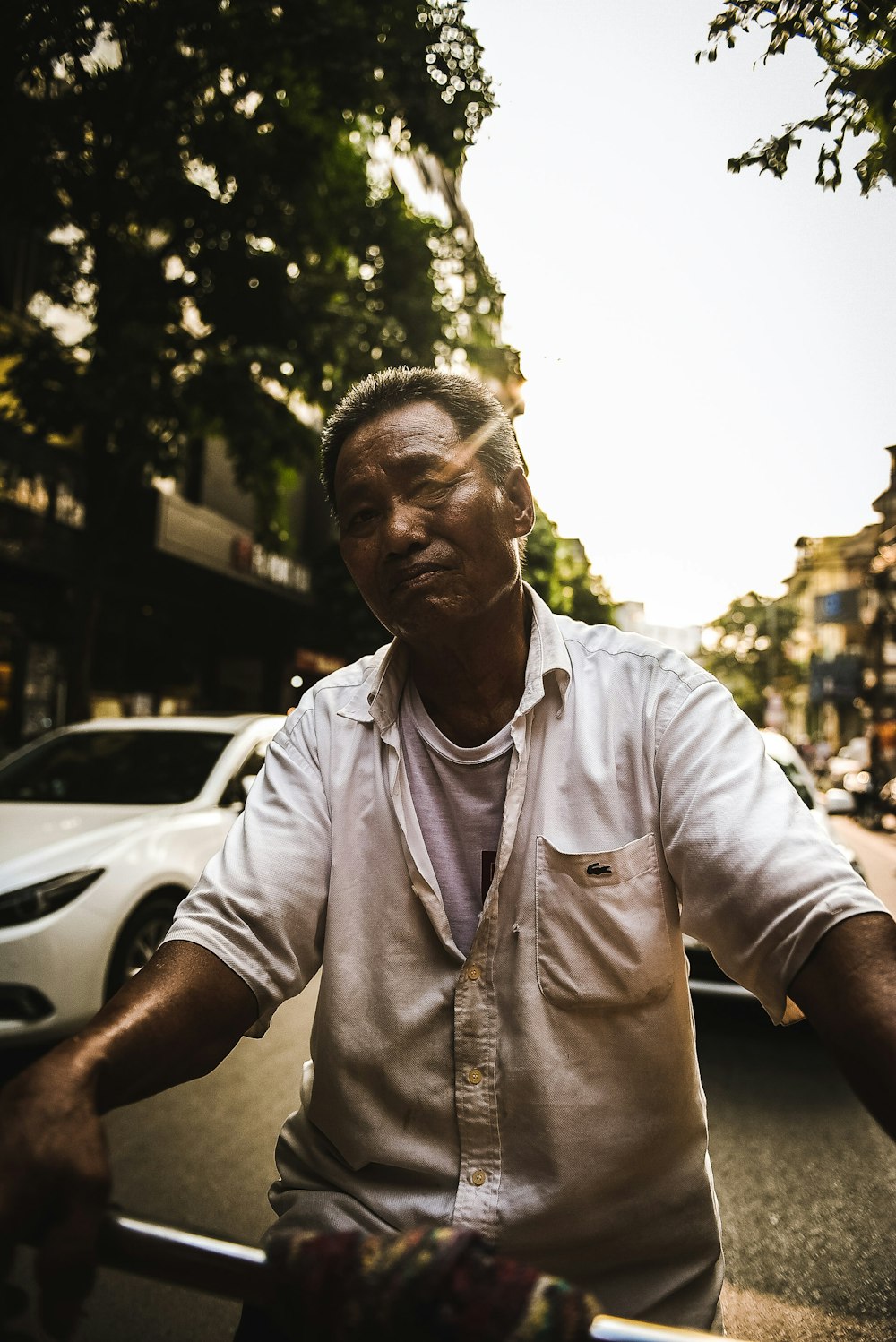 a man riding a bike down a street next to a white car