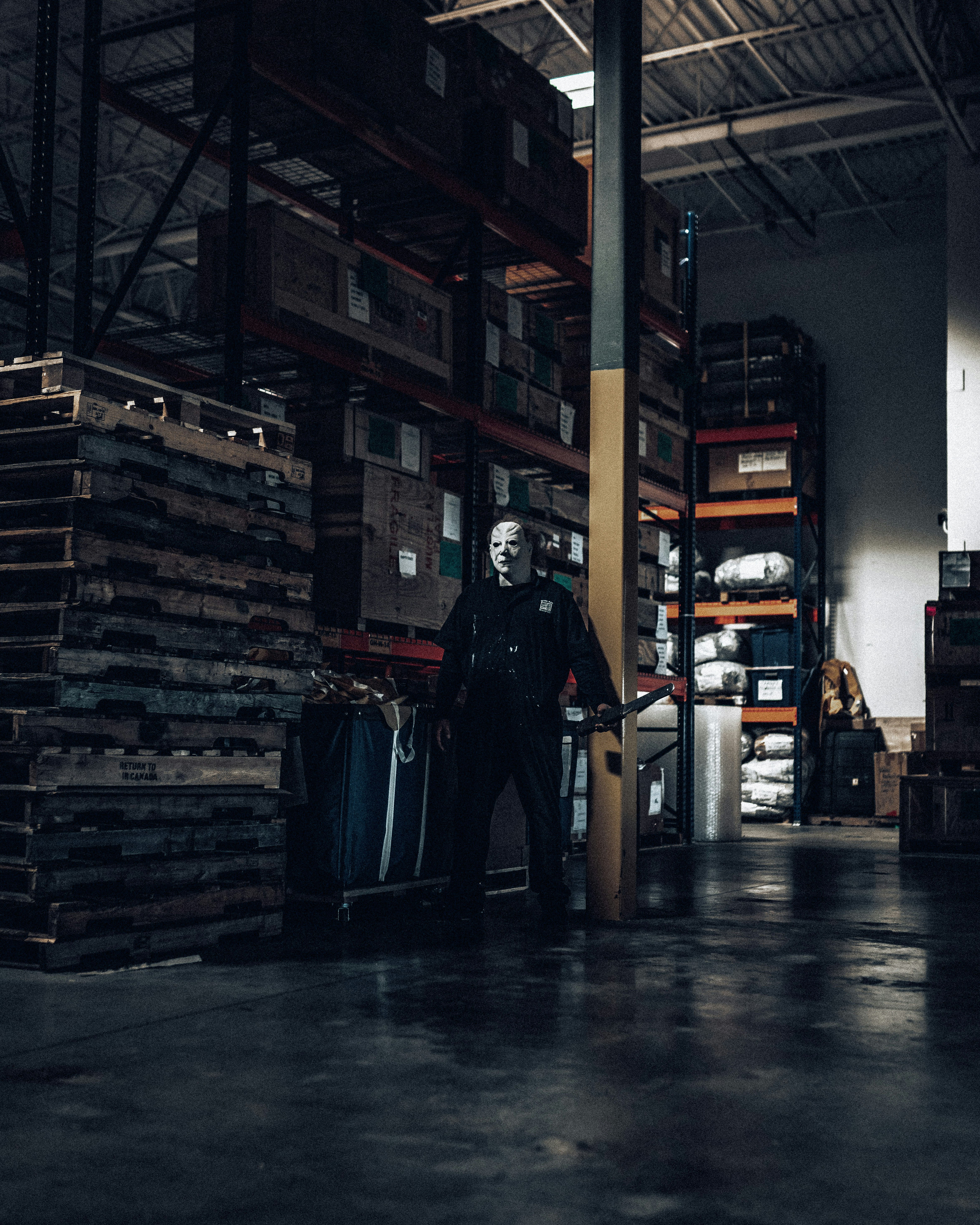 man in black leather jacket standing near black wooden shelf