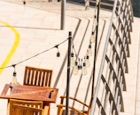 A sunlit patio with string lights and a wooden dining table set for an evening meal.