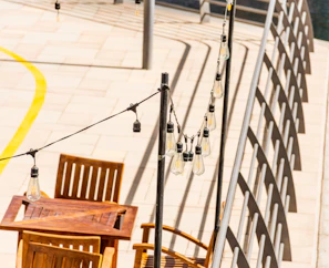A sunlit patio with string lights and a wooden dining table set for an evening meal.